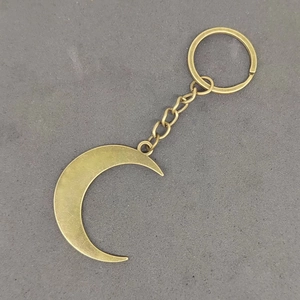 Detailed view of a vintage bronze crescent moon keychain on a textured gray background