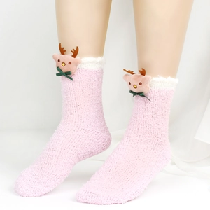 Nahaufnahme von Plüschsocken aus Korallenvlies in Rosa mit 3D-Rentier und grünen Schleifen