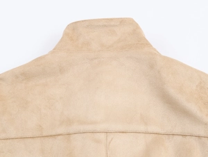 Détail du col et de l'épaule d'une veste en daim beige montrant la texture douce