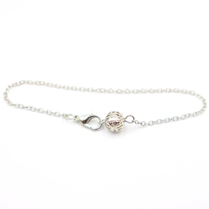 Detail view of silver hollow ball pendant on chain with lobster clasp for yoga jewelry