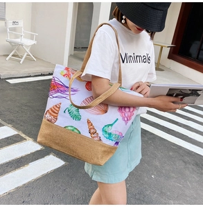 Close-up of canvas tote bag with ocean prints and brown straps on a walking model