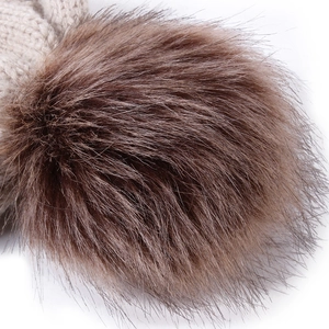 Close-up of fluffy brown faux fur pompom detail on beige knit winter beanie hat