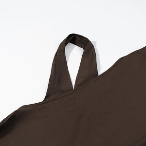 Detailed view of dark brown pleated fabric with thin shoulder strap and neckline texture