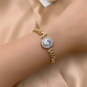 Detailed view of a gold cubic zirconia bracelet with a radiant sunflower charm on satin