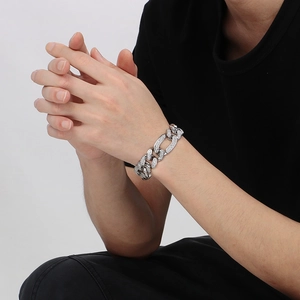 Gros plan d'un bracelet gourmette argenté orné de strass brillants sur un poignet homme