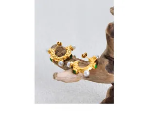 Détail de boucles d'oreilles vintage en C dorées avec perles, pierres vertes et martelées