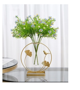 Golden metal ring vase with ginkgo leaf and bird detail featuring artificial flowers