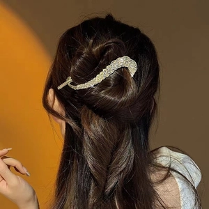 Detail of elegant gold wavy hair clip with sparkling rhinestones in a twisted design
