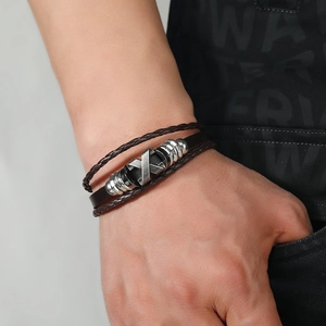 Men's multi-layer brown leather woven bracelet with silver metal X charm on wrist