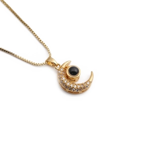 Collier en plaqué or avec pendentif lune et zircon œil maléfique sur fond blanc