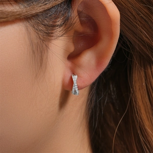 Close-up of 925 sterling silver crisscross hoop earrings with pavé zircons on ear