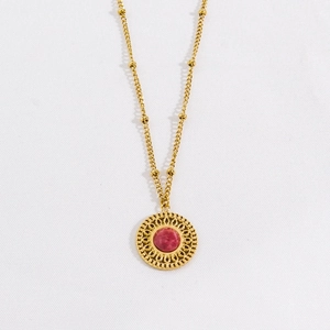 Detailed close-up of a vintage gold pendant necklace with faceted pink stone and sunburst pattern