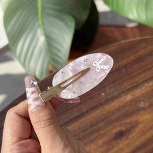Detail view of pink marble acetate hair clip with rhinestones and golden metal jaw