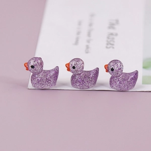 Detailed view of three purple glitter resin mini ducks for DIY micro landscape decor