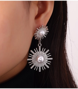 Detail of silver sunburst drop earrings with white pearls on a model close-up