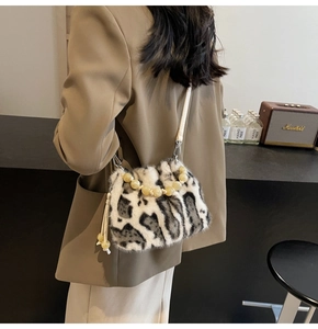 Detail of faux fur bucket bag with animal print, beaded handle and leather strap
