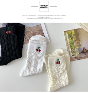 Close-up of red cherry embroidery and knit texture on black and white cotton socks