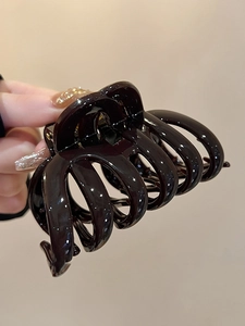 Macro detail of large brown striped acrylic hair claw clip for thick hair styling