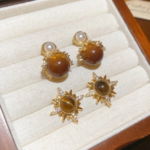 Retro 18K gold plated earrings with tiger eye stone and pearl on a beige jewelry tray