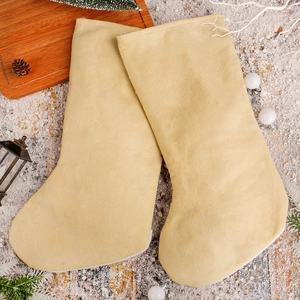 Set di due calze natalizie in peluche beige su sfondo di legno con decorazioni festività
