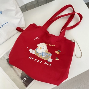 Detail of red canvas tote bag featuring cute cartoon embroidery and thick fabric texture