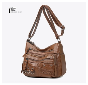 Detail of dark brown woven crossbody bag featuring multiple zippers and leather texture