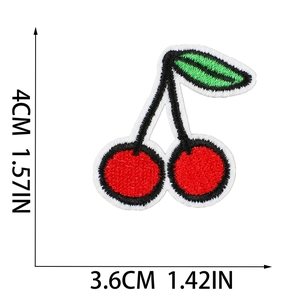 Detailed macro view showing the embroidery texture and dimensions of the red cherry patch