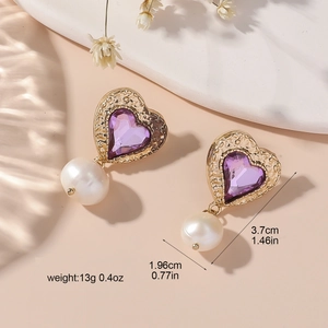 Detail of vintage heart earrings with purple gems and white pearls on a stone pedestal