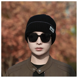 Close-up of black ribbed knit beanie with NY&JA fashion label worn by a male model