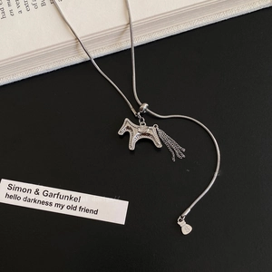 Silver horse pendant necklace with tassel detail and dollar sign charm on black background