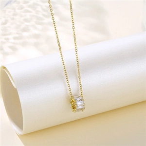 Detail view of 18K gold plated cylinder pendant necklace with sparkling zircon stones