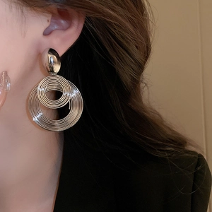 Macro shot of silver layered geometric hoop earrings featuring polished concentric spiral lines