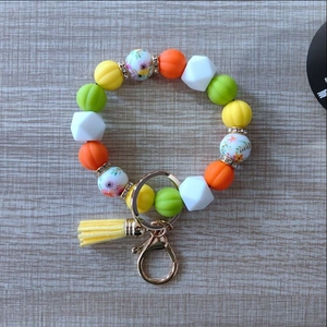Silicone bead keychain bracelet with pumpkin orange hues, tassel, and floral accents