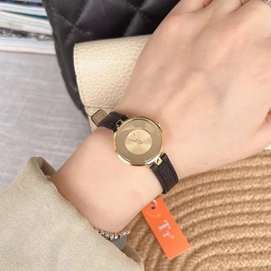 Close-up of minimalist gold ladies watch with black leather strap on a model wrist