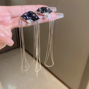 Detailed shot of black fan-shaped earrings with long silver tassels and vintage design