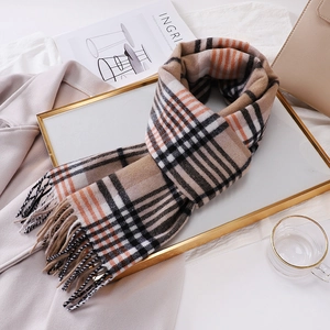 Detail of wool scarf with camel plaid pattern and fringe on a white tray