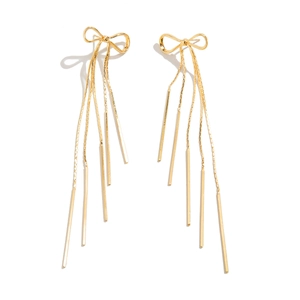 Detail shot of golden bow earrings with long metal tassels showing a polished finish