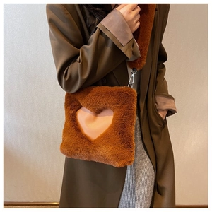 Dettaglio borsa quadrata in peluche marrone con intaglio a cuore rosa e tracolla soffice