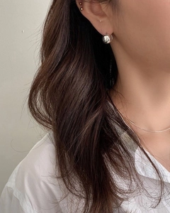 Polished silver sphere stud earrings and minimalist thin necklace worn by a model