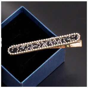 Detail view of a metal hair clip with gradient black and white rhinestone pave setting