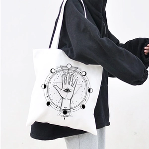 Detail of white canvas tote bag featuring black mystical demon eye and celestial prints