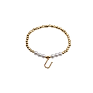 Detail view of gold bead bracelet with pearls and horseshoe charm with colored crystals