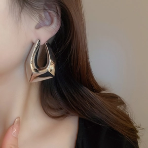Gros plan sur de grandes boucles d'oreilles géométriques argentées au design trapèze