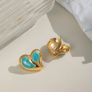 Makroaufnahme goldener Herzohrringe mit blauem Marmor-Design auf geriffeltem Glas