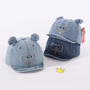 Détail de la casquette bébé en denim avec oreilles d'ours 3D et broderie lunettes