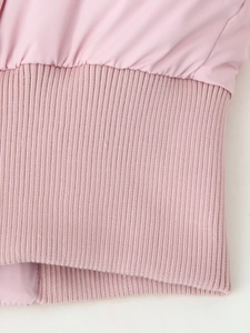 Detail of pink cotton jacket featuring ribbed knit cuffs and hem stitching texture