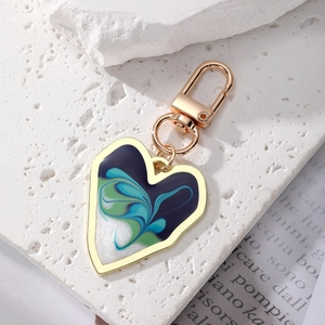 Bohemian gold heart keychain with blue enamel fluid art on white stone background