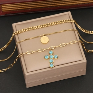 Three-layer gold necklace with turquoise cross pendant and round coin on jewelry box