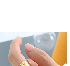 Macro view of a tiered wave texture ring in 18K gold plated finish worn on finger