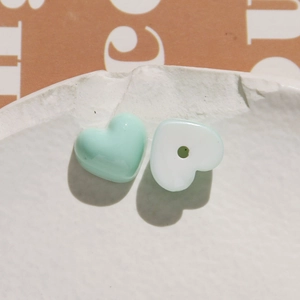 Macro shot of mint green and white resin heart charms for DIY jewelry making